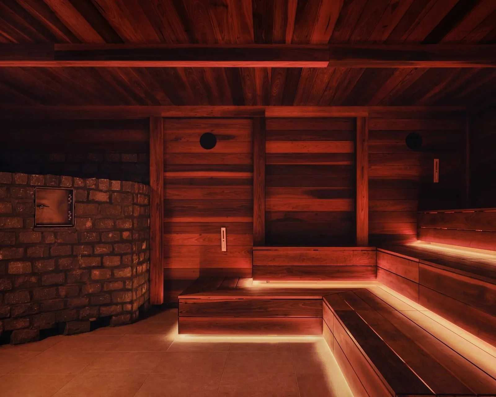 Bathhouse Philadelphia banya: a masonry stove wall beside timber-lined walls and stepped benches lit from below